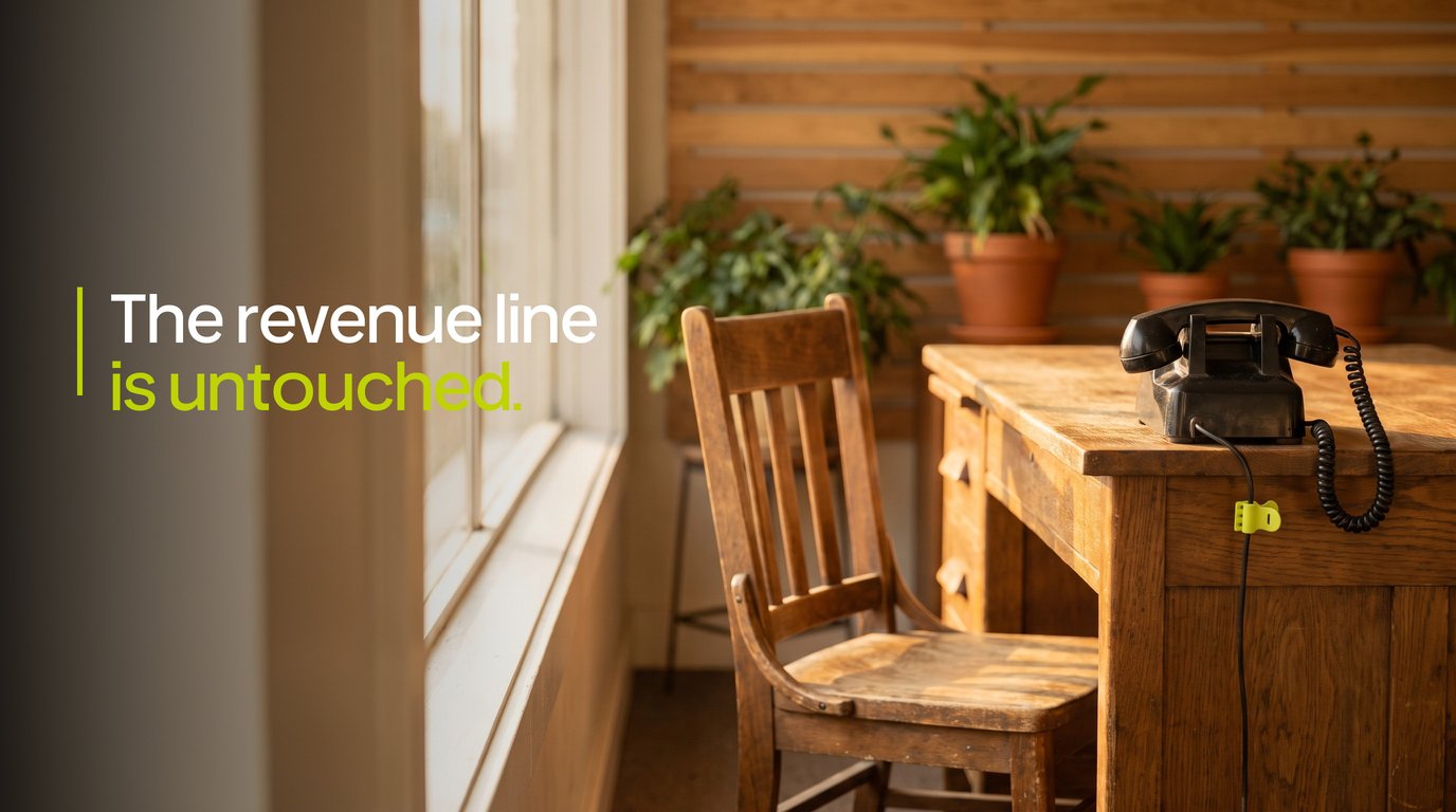A desk phone on an empty insurance agency front desk in afternoon light, with the words The revenue line is untouched